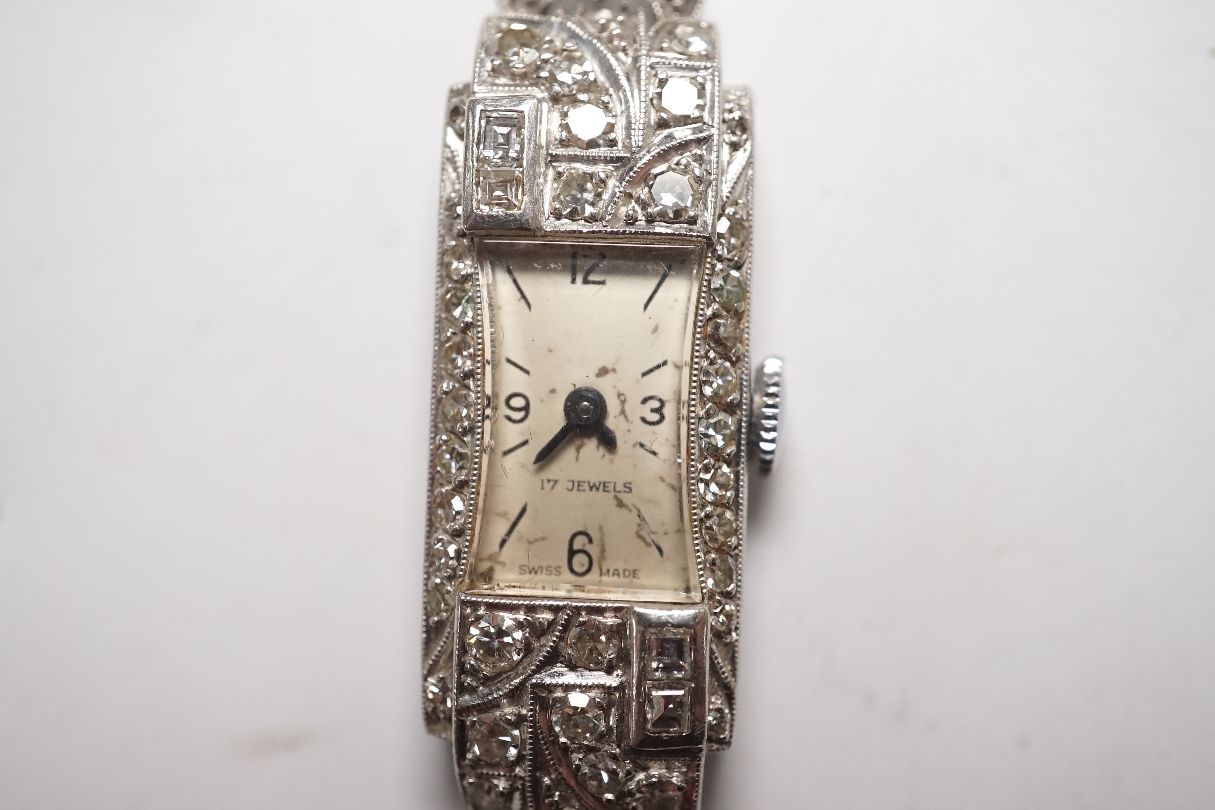 A lady's mid 20th century white metal (stamped platinum) and diamond set manual wind cocktail watch, on a 9ct white metal twin strand bracelet, overall length 16.5cm, gross weight 17.6 grams/ Condition - fair to good